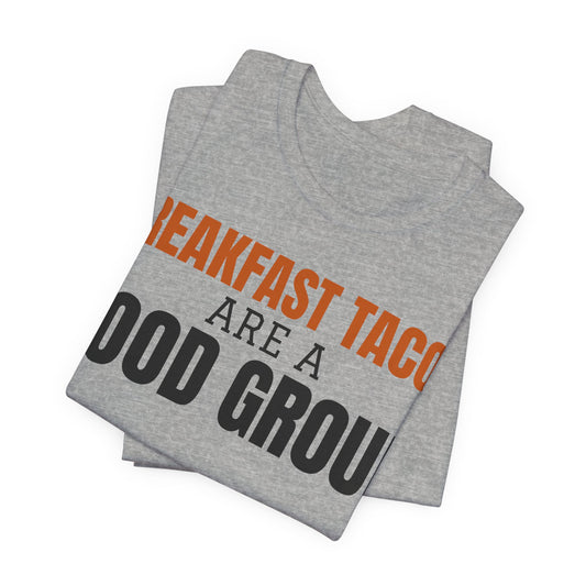 Folded heather gray tee with large orange/black 'Breakfast Tacos are a Food Group' text graphic