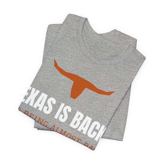 Athletic heather graphic tee showing 'Texas Is Back*' text and orange longhorn