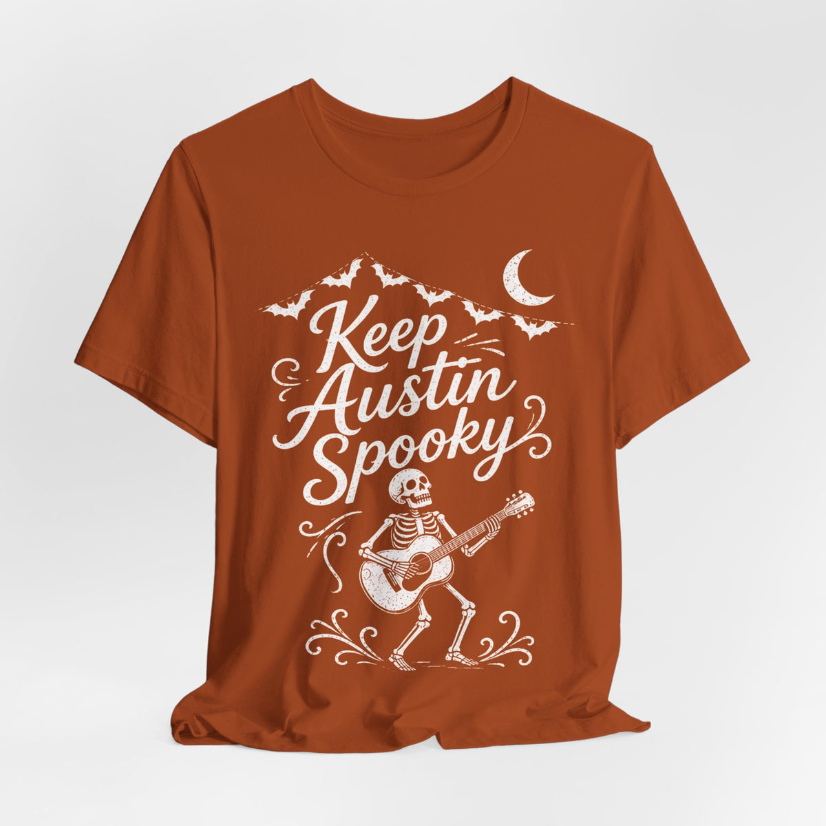 Rust orange crewneck tee featuring white "Keep Austin Spooky" skeleton with guitar