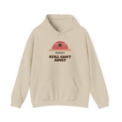 Sand-colored pullover hoodie with “Graduated” and “Still Can’t Adult” chest graphic