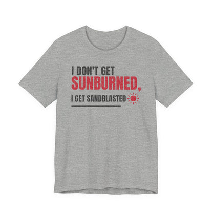 Gray crew-neck T-shirt with 'I DON'T GET SUNBURNED' and 'I GET SANDBLASTED' graphic