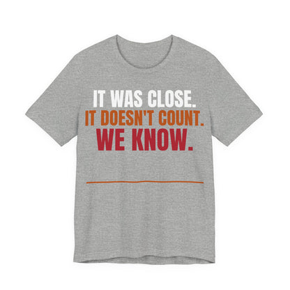 Athletic heather graphic tee with "IT WAS CLOSE" slogan in white, orange, and red