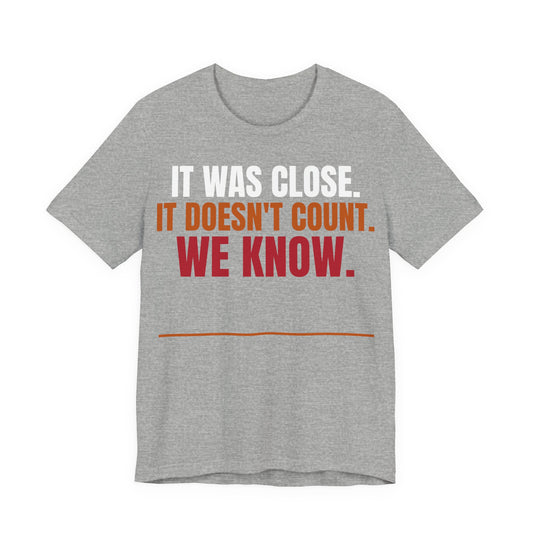 Athletic heather graphic tee with "IT WAS CLOSE" slogan in white, orange, and red