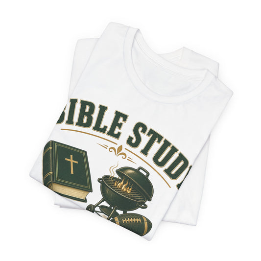 White folded T-shirt with 'Bible Study' graphic, green book, grill, and football emblem