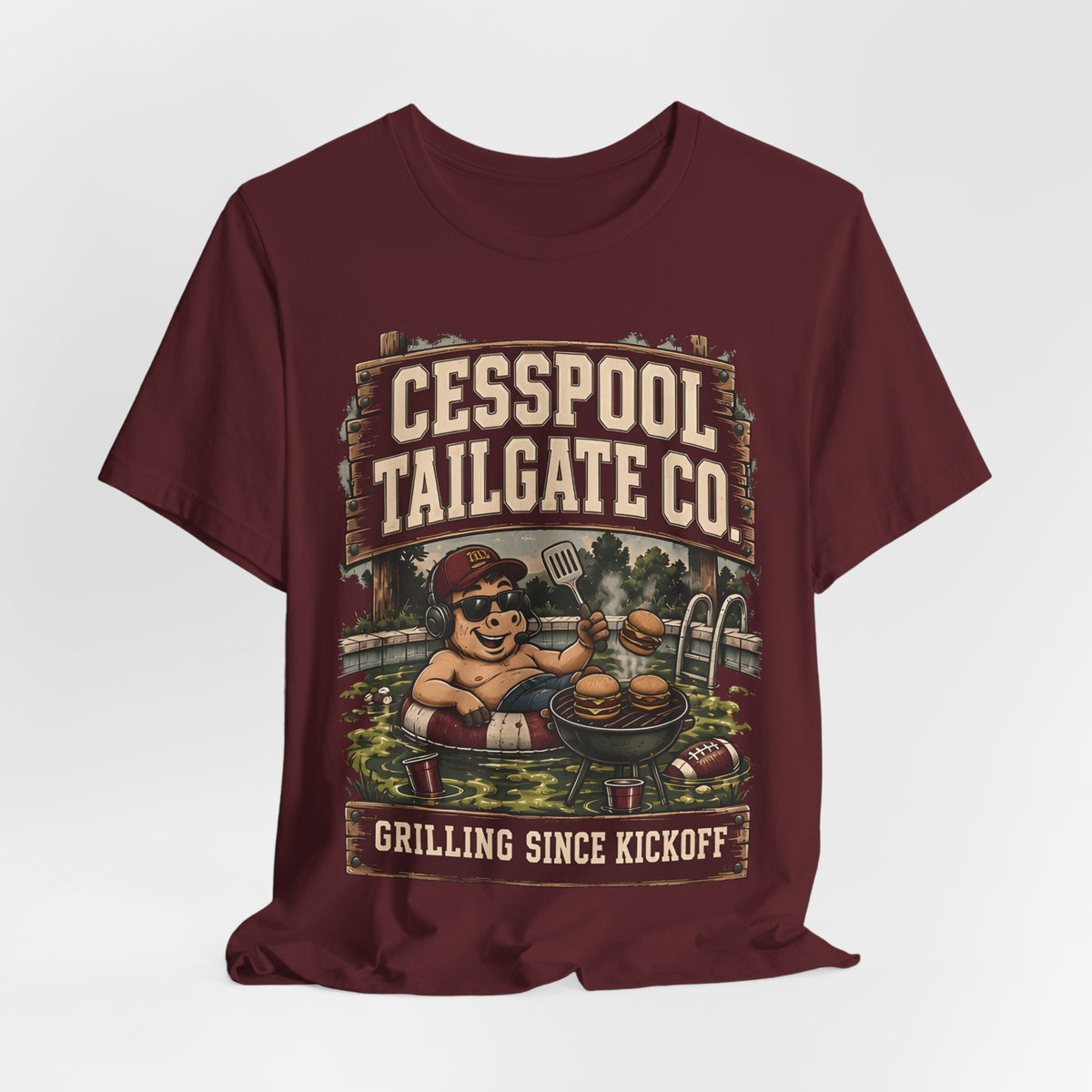 Burgundy graphic T-shirt with cartoon pitmaster and Cesspool Tailgate Co. front print