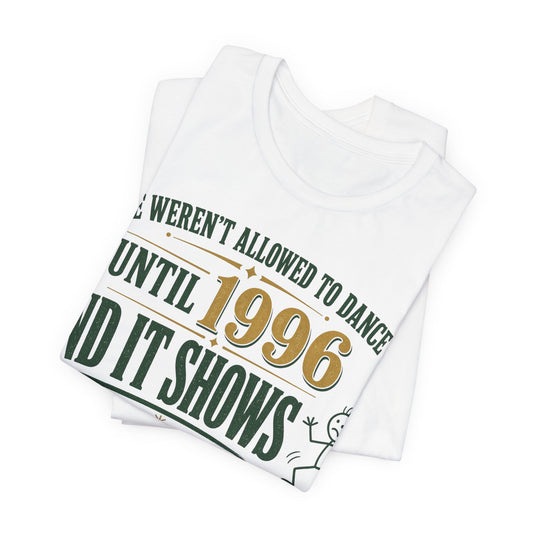Folded white tee with green "UNTIL 1996" slogan and dancing character graphic