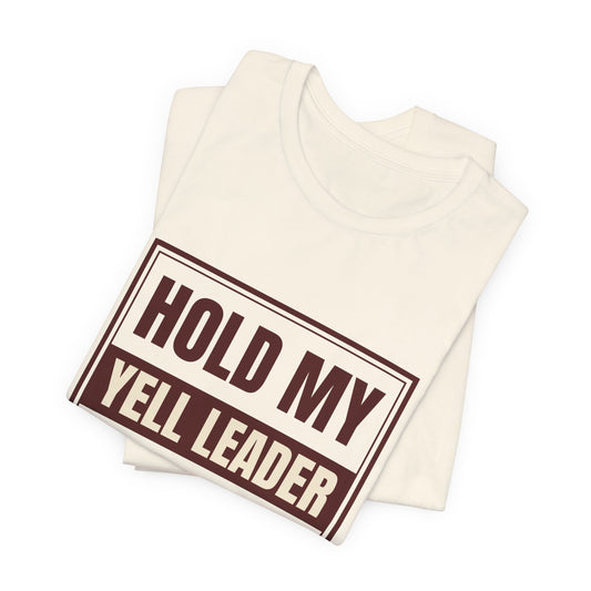 Natural crewneck tee folded; close-up of "HOLD MY YELL LEADER" graphic