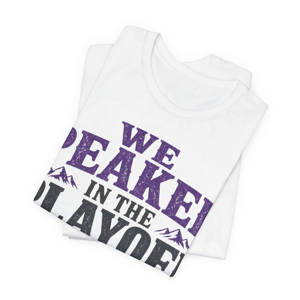 White folded T-shirt with large purple and black 'WE PEAKED' in-playoff print
