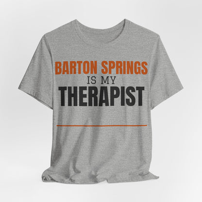 Heather gray crew-neck T-shirt with orange 'Barton Springs' and black 'Therapist' text